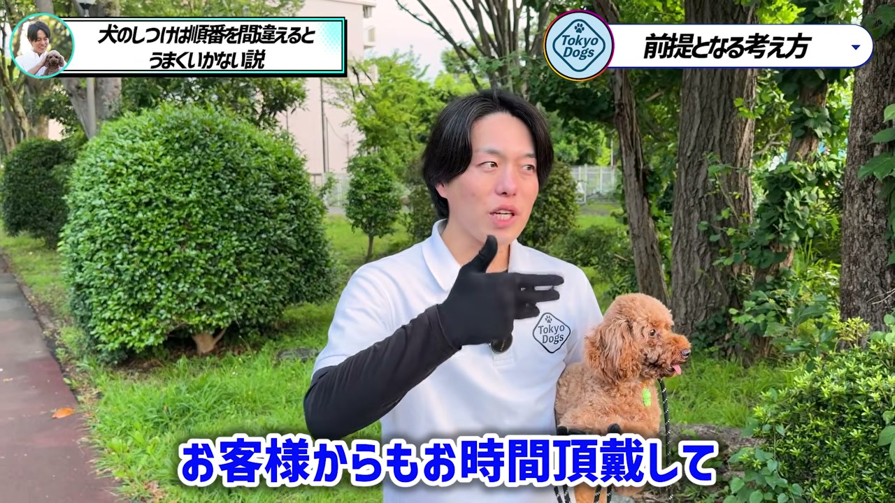 トイプードルを抱き、屋外で飼い主の相談について説明する松尾邑仁