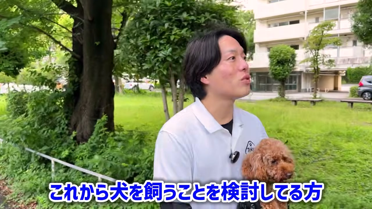 トイプードルを抱き、犬を迎える前の飼い主へ話す松尾邑仁