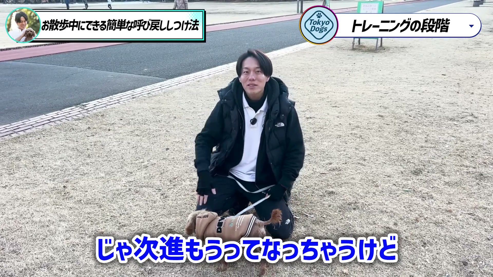 リードを持ち、犬のそばで練習の段階を説明する松尾邑仁